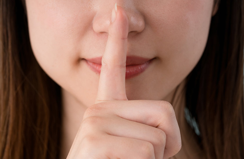 写真：女性が唇に人差し指を当てて、秘密をイメージさせるポーズをとっている